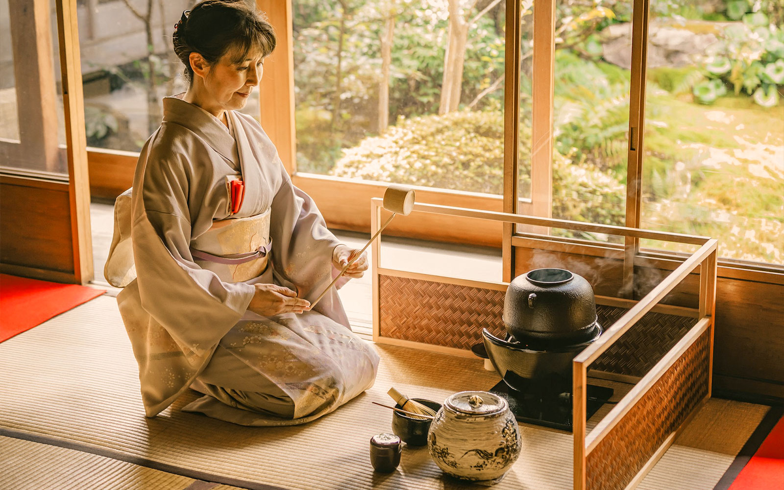 Woman in kimono performing tea ceremony in Kyoto teahouse.