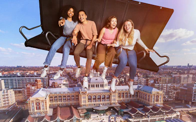 People enjoying a flight simulation ride at THIS IS HOLLAND with Amsterdam cityscape below.