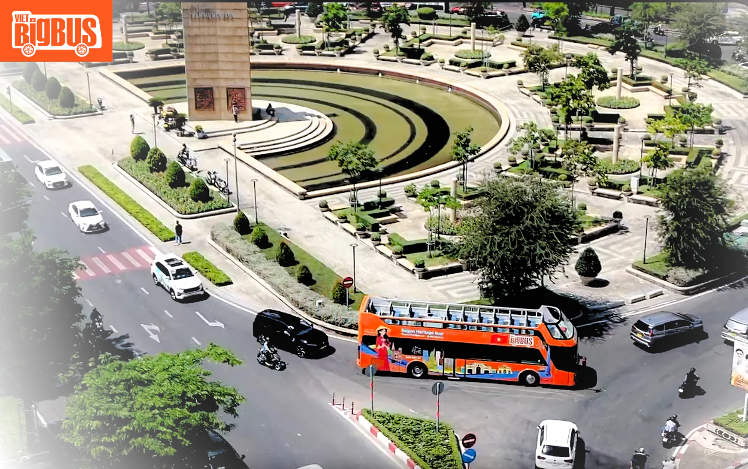 Open-top tour bus near a monument in Ho Chi Minh City, part of the Heritage Sightseeing Loop.