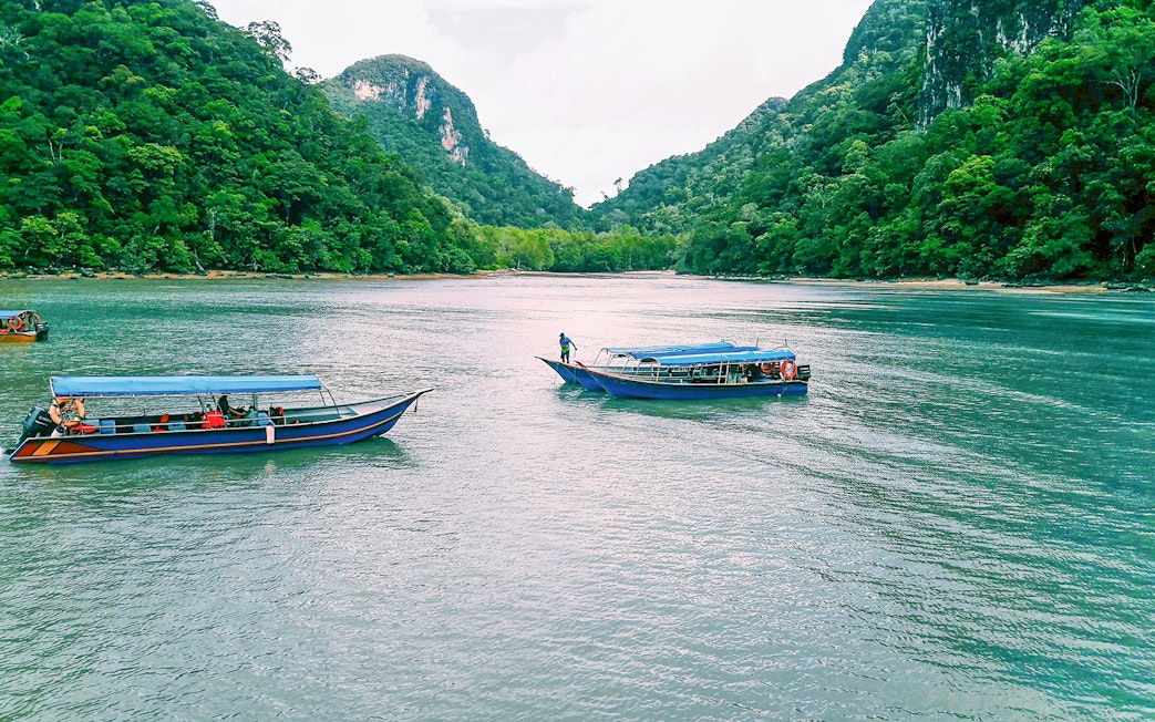 Speedboats on Langkawi mangrove tour with lush green hills in the background.