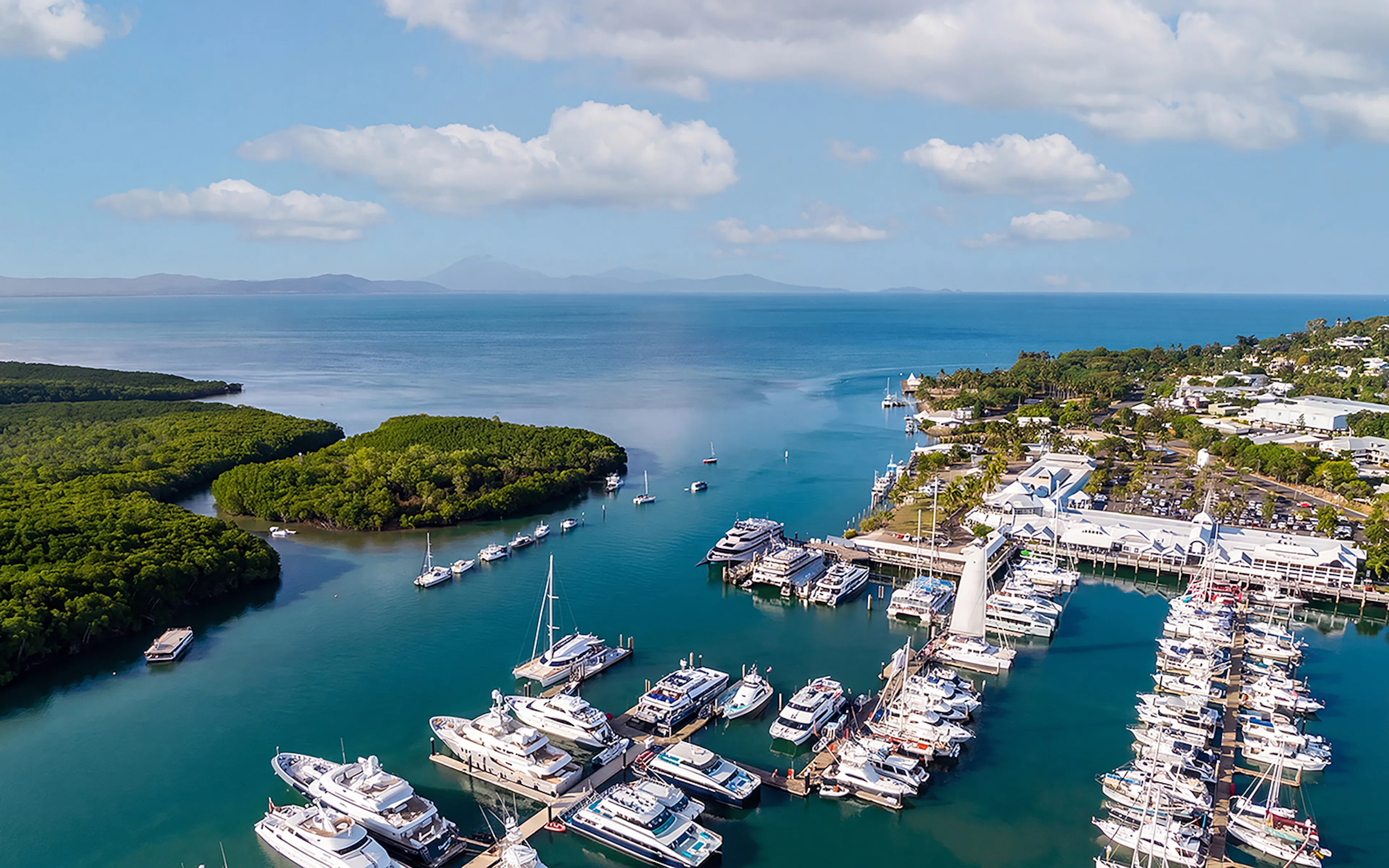 Aerial view of yachts and boats at Cairns Port Douglas marina with mountain landscape, Queenstown, Australia.