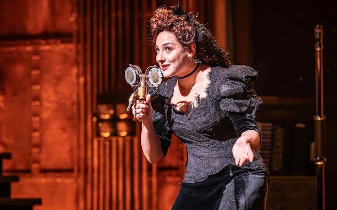 Performer on stage during Hadestown show, West End, holding a vintage microphone.