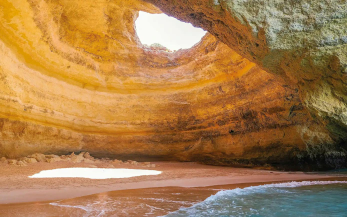 Benagil Cave with sunlight through ceiling opening, Algarve, Portugal.
