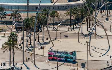Barcelona hop-on hop-off bus near waterfront and modern sculpture.