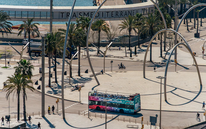 Barcelona hop-on hop-off bus near waterfront and modern sculpture.