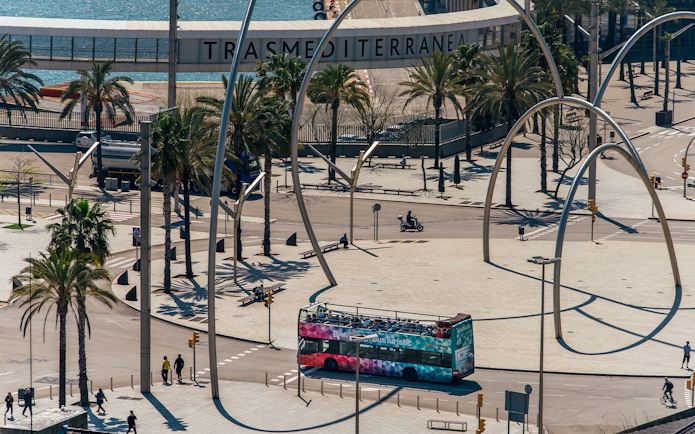 Barcelona hop-on hop-off bus near waterfront and modern sculpture.