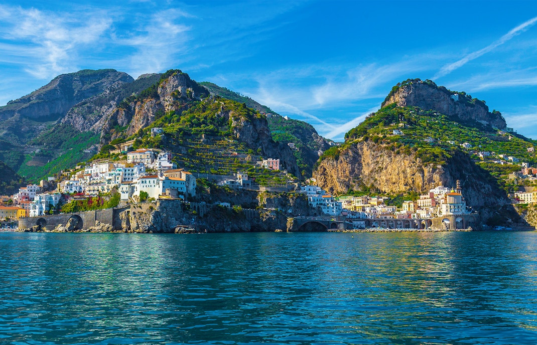 Coastal village and cliffs along the Amalfi Coast, Italy, with clear blue sea.