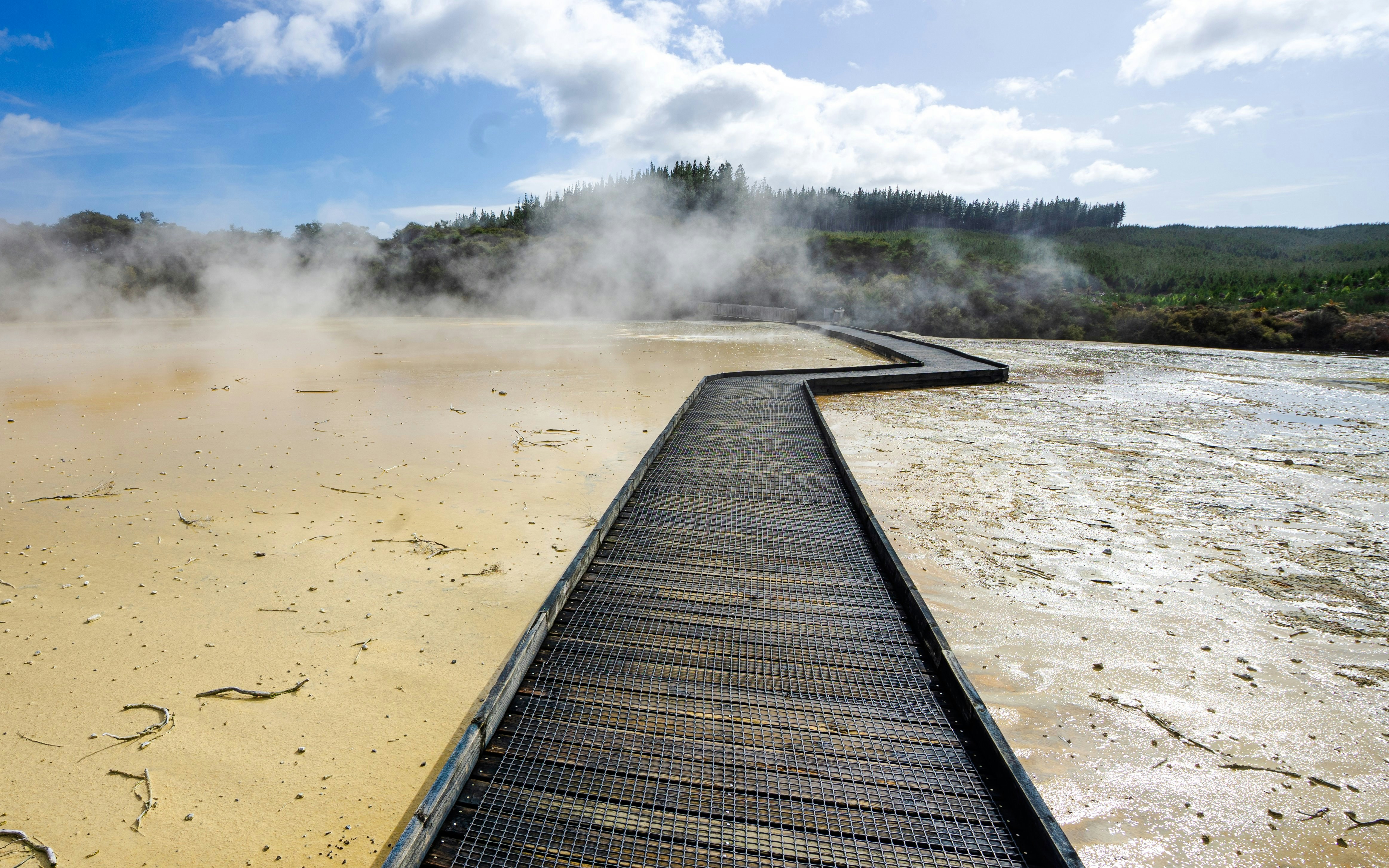 Wooden path through steaming travertine at Wai o Tapu, New Zealand.