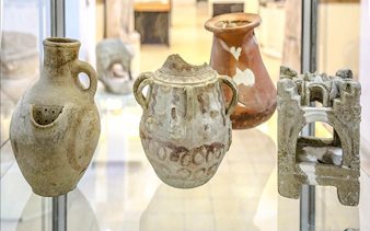 Ancient pottery artifacts displayed in Amman museum during city sightseeing tour.