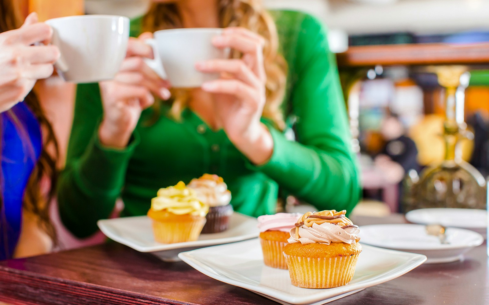 Two people enjoying coffee and cupcakes at a café table.