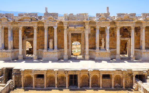 Ancient amphitheater facade with columns and statues in Hierapolis, Turkey.