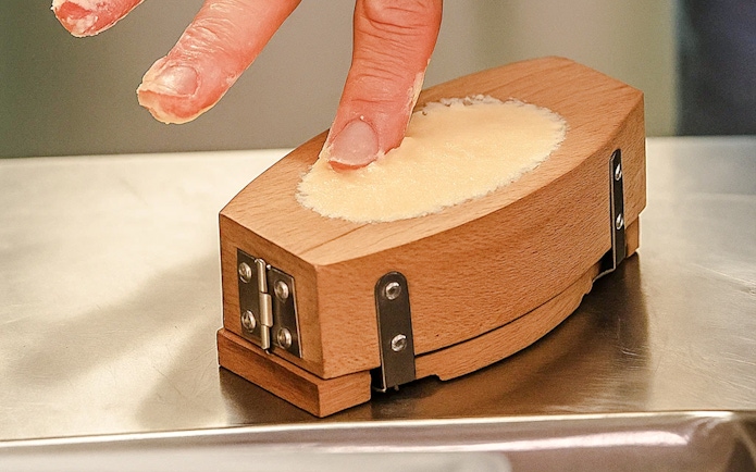 Person shaping butter in a wooden mold at the Cheese Museum, Paris, France.
