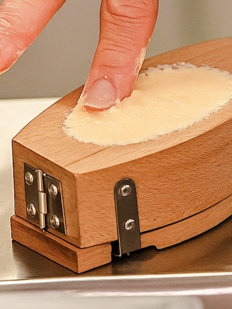 Person shaping butter in a wooden mold at the Cheese Museum, Paris, France.