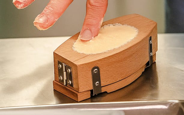 Person shaping butter in a wooden mold at the Cheese Museum, Paris, France.