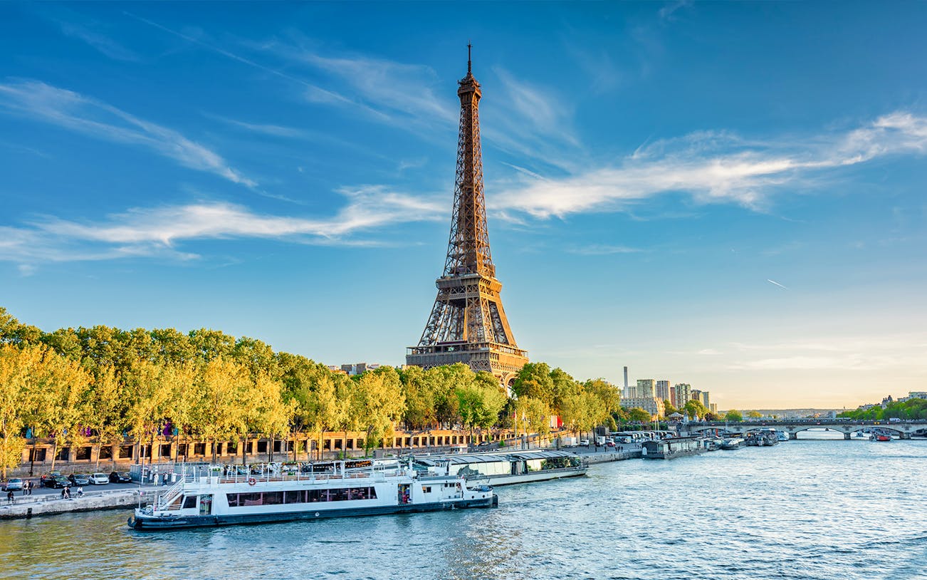 Eiffel Tower beside the Seine River with boats in Paris, France.