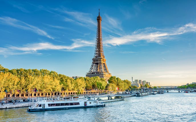 Eiffel Tower beside the Seine River with boats in Paris, France.
