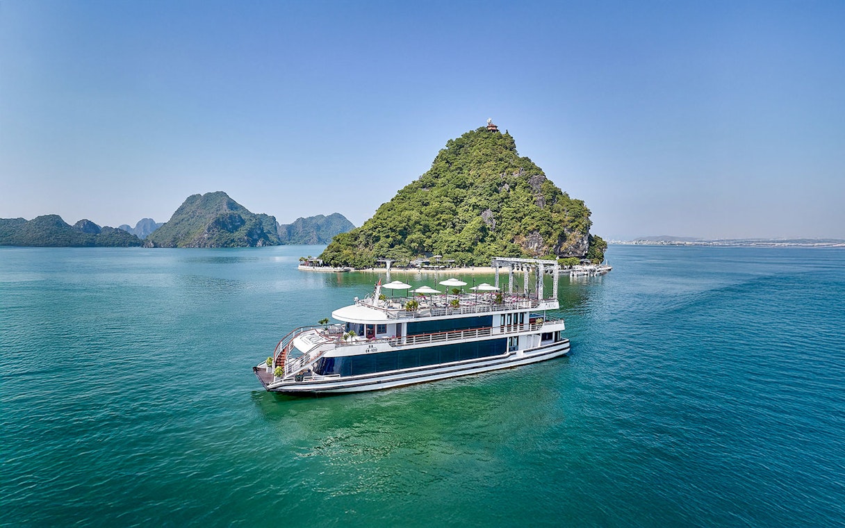 Cruise ship sailing in Ha Long Bay with limestone islands in the background.