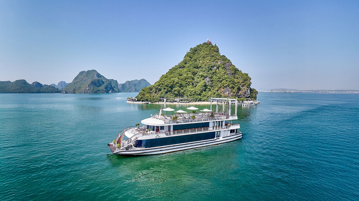 Cruise ship sailing in Ha Long Bay with limestone islands in the background.
