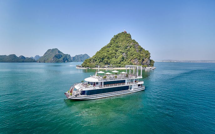 Cruise ship sailing in Ha Long Bay with limestone islands in the background.