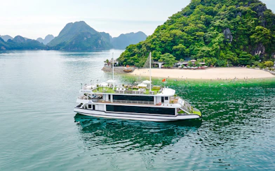 Cruise ship Hercules Premium near a scenic island with lush greenery and a sandy beach.