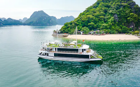 Cruise ship Hercules Premium near a scenic island with lush greenery and a sandy beach.