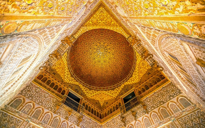 Intricate ceiling of the Alcazar of Seville with detailed geometric patterns.
