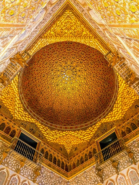 Intricate ceiling of the Alcazar of Seville with detailed geometric patterns.