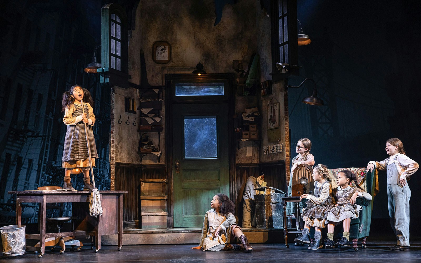 Children performing a scene from the musical "Annie" on stage.