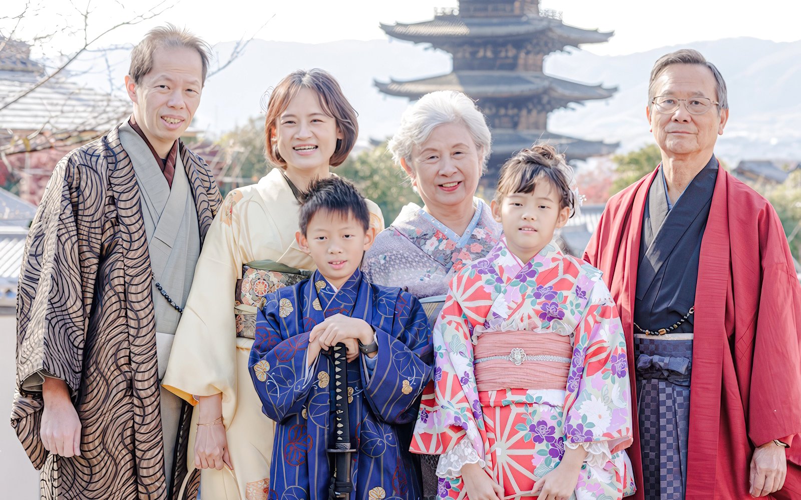 Family in traditional kimonos posing in front of a pagoda in Kyoto.