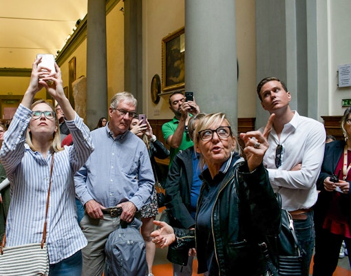 Tour guide explaining Michelangelo's David to visitors at Accademia Gallery, Florence.