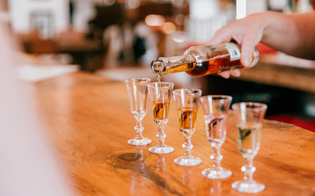 Pouring spirits into glasses on a wooden table at Tamborine Mountain tasting tour.
