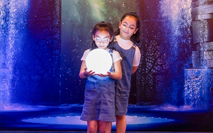 Children holding a glowing orb at La Perle by Dragone show.