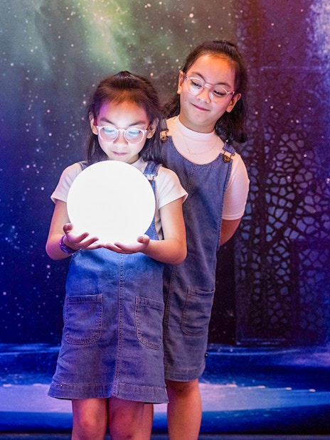 Children holding a glowing orb at La Perle by Dragone show.