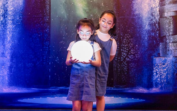 Children holding a glowing orb at La Perle by Dragone show.