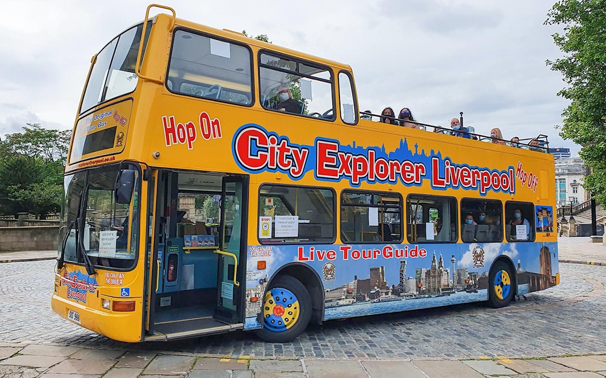 Open-top City Explorer Liverpool tour bus on cobblestone street.