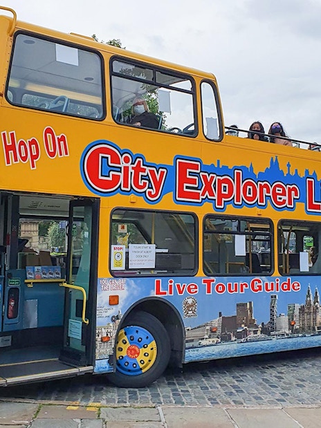 Open-top City Explorer Liverpool tour bus on cobblestone street.
