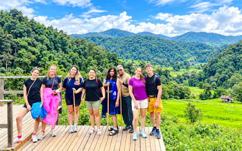 Group of tourists on a wooden deck with lush green hills in Doi Inthanon, Chiang Mai.