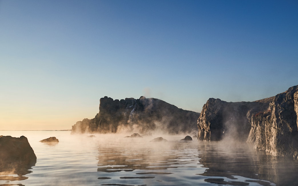 Sky Lagoon with mist rising from water, rocky cliffs in Saman Pass.