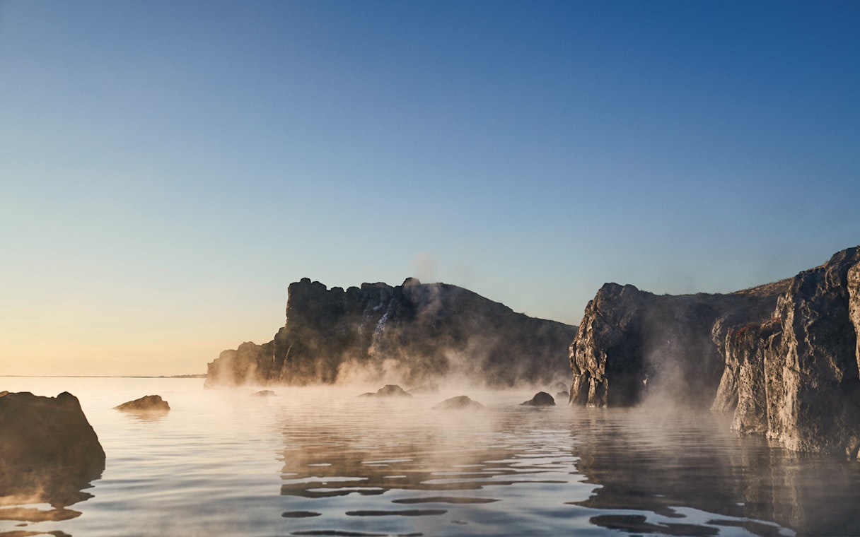 Sky Lagoon with mist rising from water, rocky cliffs in Saman Pass.