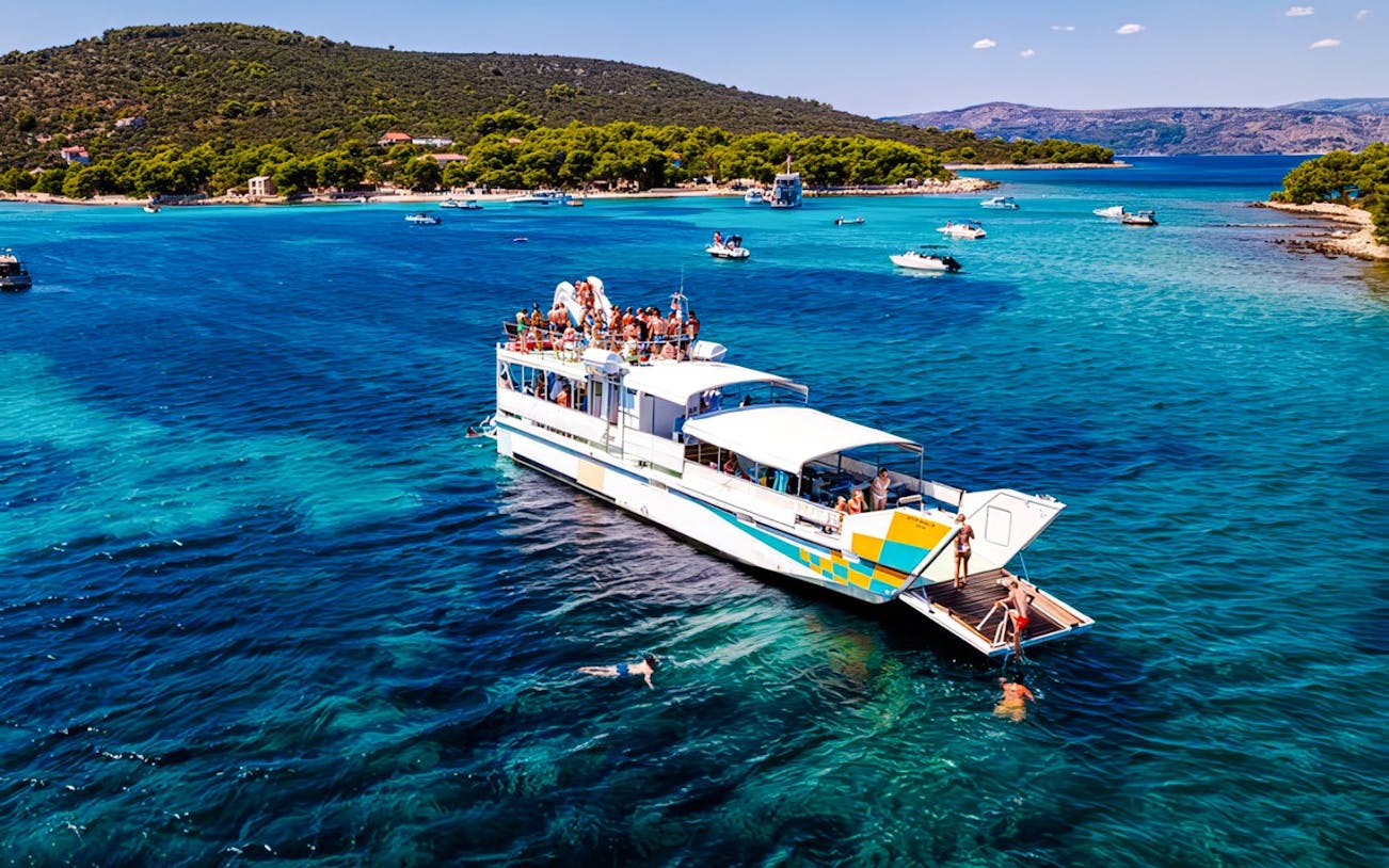 Cruise ship on Blue Lagoon tour from Split with swimmers in clear water.