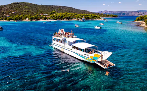 Cruise ship on Blue Lagoon tour from Split with swimmers in clear water.