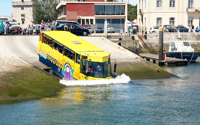 Amphibious tour bus entering water during Lisbon sightseeing guided tour.