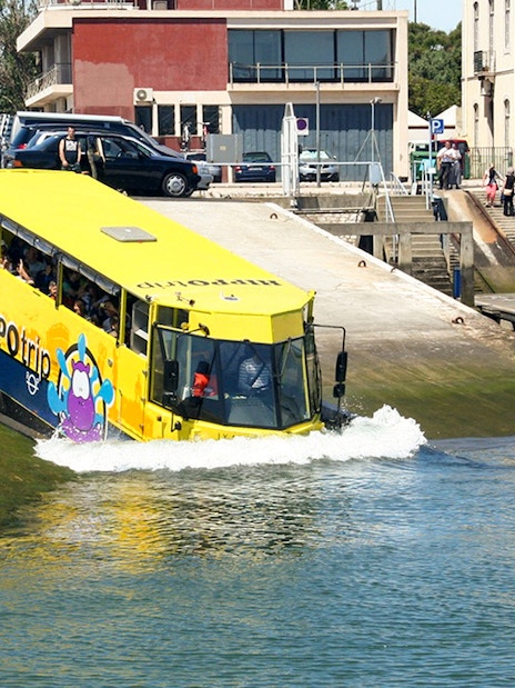 Amphibious tour bus entering water during Lisbon sightseeing guided tour.