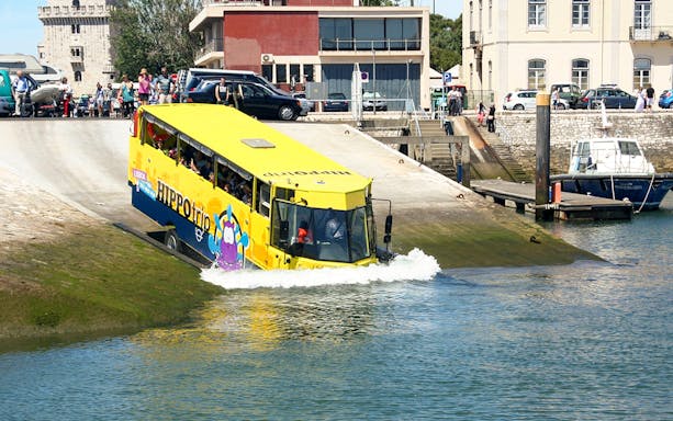 Amphibious tour bus entering water during Lisbon sightseeing guided tour.