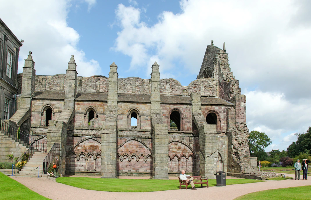Holyrood Abbey ruins with visitors exploring the historic site in Edinburgh, Scotland.