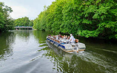Guests on a motorboat tour along Karl Heine Canal, Leipzig, surrounded by lush greenery.