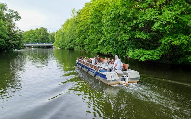 Guests on a motorboat tour along Karl Heine Canal, Leipzig, surrounded by lush greenery.