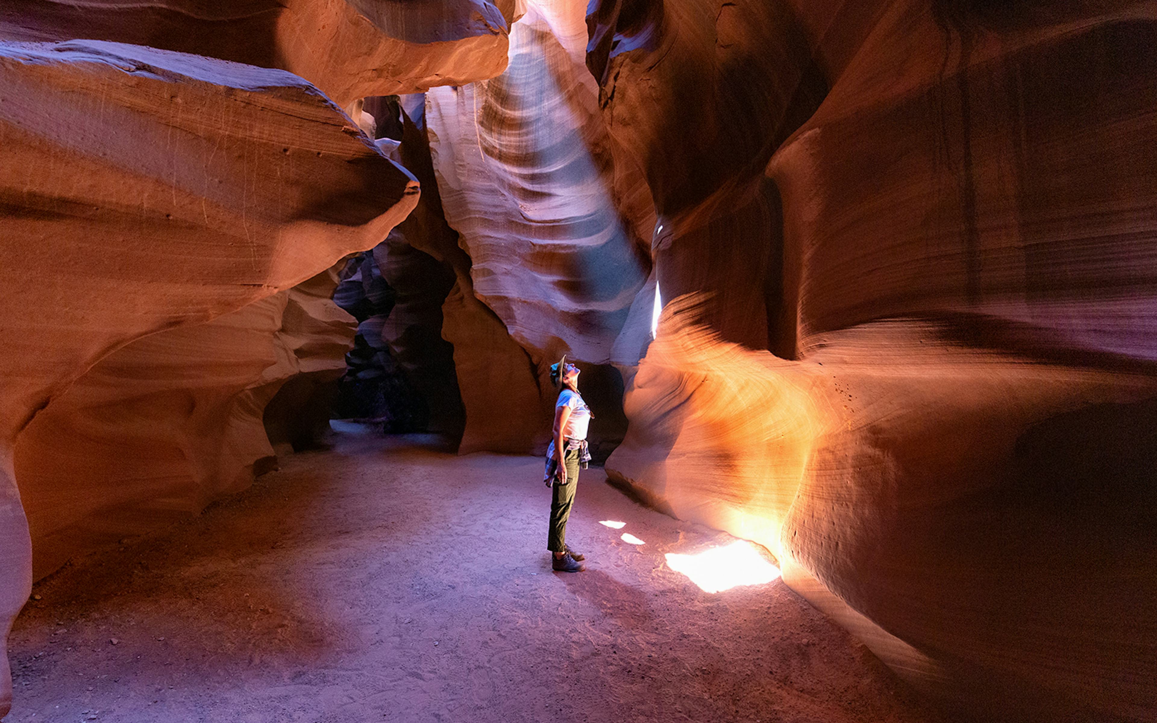 Person exploring Antelope Canyon's illuminated sandstone walls, Arizona.