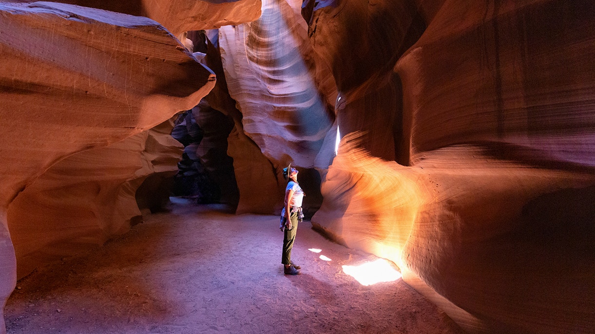 Person exploring Antelope Canyon's illuminated sandstone walls, Arizona.