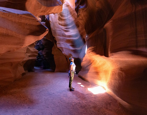 Person exploring Antelope Canyon's illuminated sandstone walls, Arizona.
